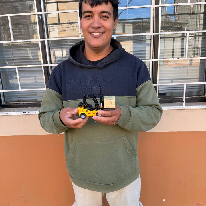 Colaborador com miniatura de empilhadeira em treinamento