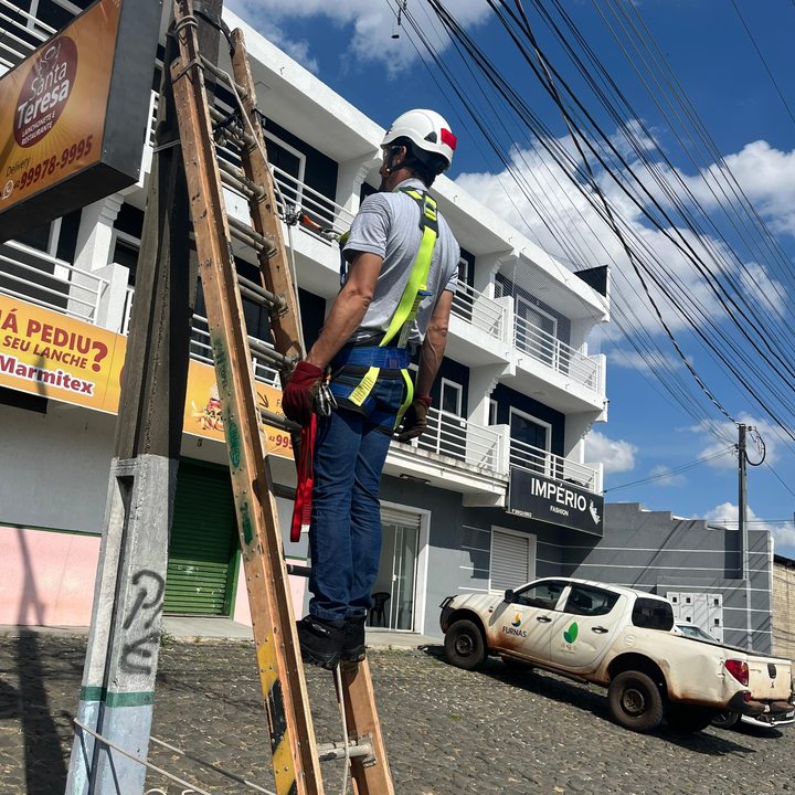 Técnico em escada com cinto de segurança em via pública